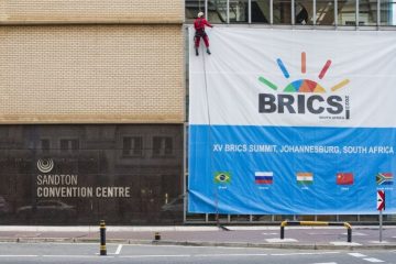 A worker arranges a signboard of the 15th BRICS summit outside the Sandton Convention Center in Johannesburg