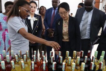 Chinese ambassador to Tanzania Chen Mingjian (C) listens to introduction to products of a Tanzanian enterprise at a farewell ceremony for Tanzanian exhibitors held at the Chinese Embassy in Dar es Salaam, Tanzania