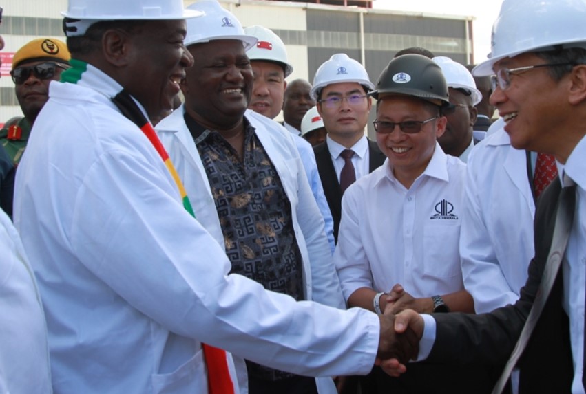 Zimbabwean President Emmerson Mnangagwa (L) shakes hands with a staff member from China's Sinomine Resource Group at Bikita Lithium Mine in Masvingo Province, Zimbabwe