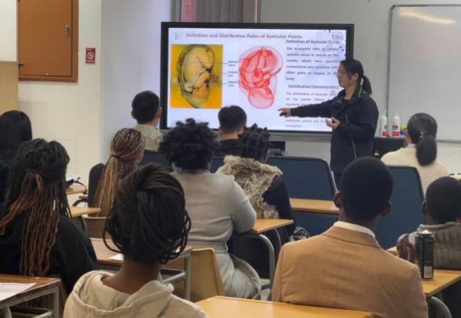 Ding Jumei, in front of the classroom, guides students through a hands-on traditional Chinese medicine (TCM) ear acupressure session at the Confucius Institute of the University of Namibia in Windhoek